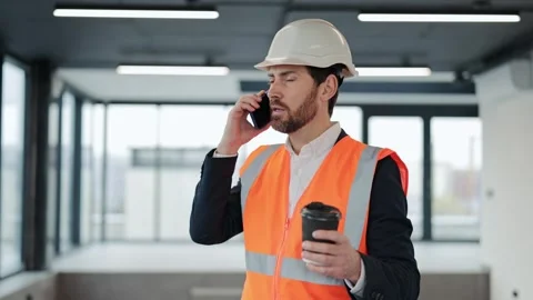 Professional Engineer in Hard Hat and Vest Drinks Coffee and Uses Smartphone in Stock-Footage 308157447