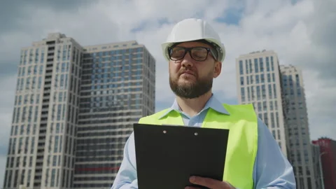 Professional engineer in hard hat looking up at buildings on construction site Stock Footage 345151100