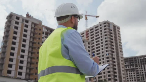 Professional engineer in hard hat writing on clipboard at construction site Stock Footage 341952703