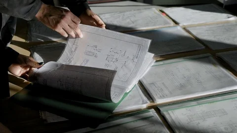 Professional engineer looking over blueprints on the table, lots of a document Stock Footage 100390342