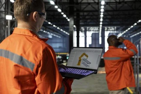 Professional engineer reviews robot software model on laptop Stock Photos