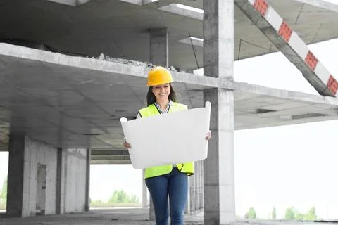 Professional engineer in safety equipment with drafting at construction site Stock Photos