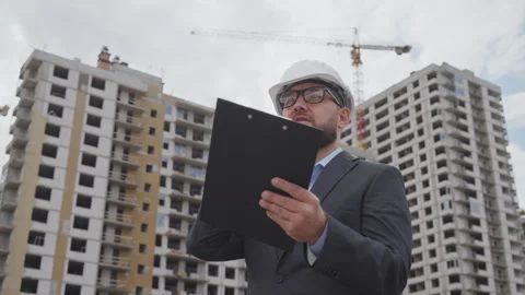 Professional engineer in suit and hard hat talking on phone at construction site Stock Footage 346815681