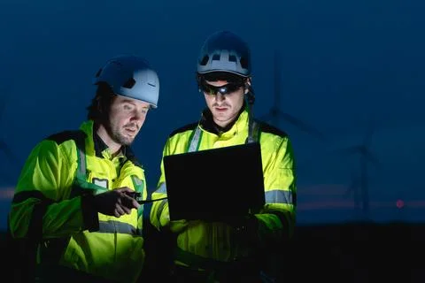 Professional engineer team at night shift. Workers in wind turbine. Technic.. Stock Photos