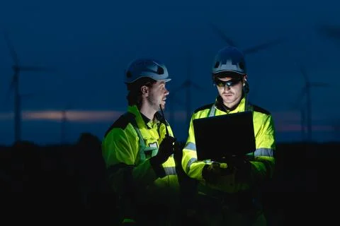 Professional engineer team at night shift. Workers in wind turbine. Technic.. Stock Photos