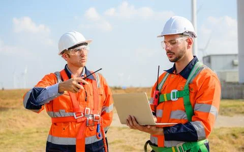 Professional engineer technician team working at wind turbine farm field Stock Photos