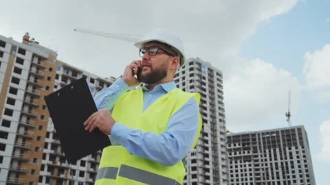 Professional engineer in white hard hat talking on phone at construction site Stock Footage 341952712