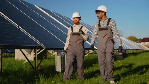 Professional engineers discussing project details near solar panel installation Stock Footage 314407482