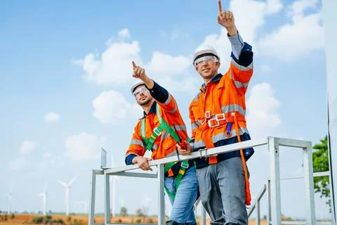Professional engineers technicians working at wind turbine farm field Stock Photos
