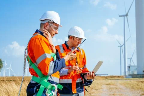 Professional engineers technicians working at wind turbine farm field Stock Photos