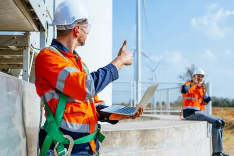 Professional engineers technicians working at wind turbine farm field Stock Photos