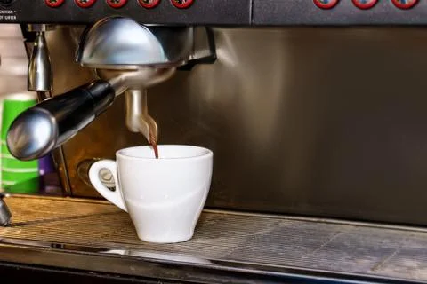 Professional espresso coffee machine makes fresh coffee and pouring it into w Stock Photos