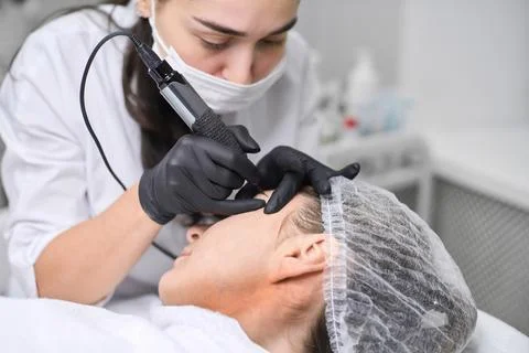 Professional eyebrow permanent makeup session in spa setting Stock Photos