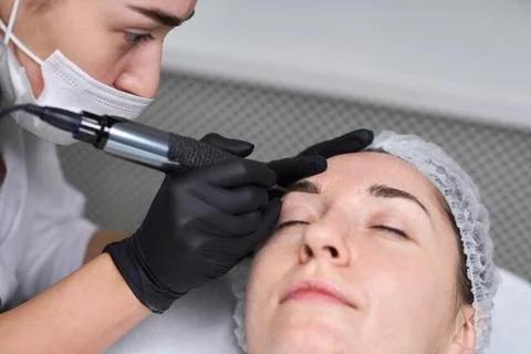 Professional eyebrow permanent makeup session in spa setting Stock Photos