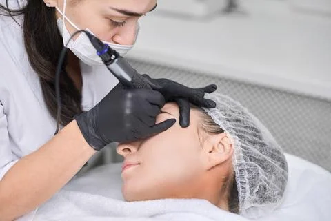 Professional eyebrow permanent makeup session in spa setting Stock Photos