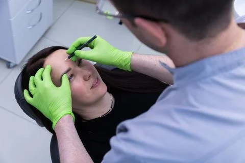 Professional Eyebrow Shaping Session: Skilled Technician Using Precision Tools Stock Photos