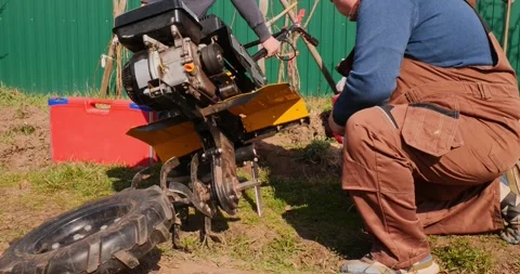 Professional farmer in work overalls removing a rubber wheel from a walk-behind 스톡 동영상 333232244