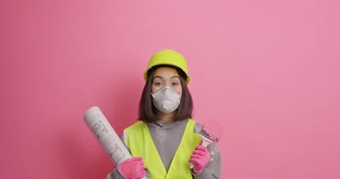 Professional female construction worker focused above on ceiling chooses paint Stock Footage 155491644