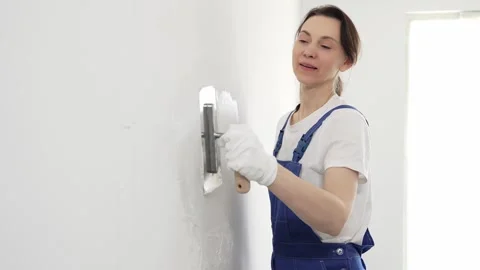 Professional female construction worker wearing blue coveralls is using a Stock Footage 309396873