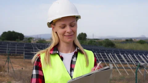 Professional female engineer in uniform standing in solar farm and using ta.. Stock Footage 333580909