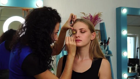 Professional female makeup artist using thin eyeshadow brush to apply bright Vidéo 102734652