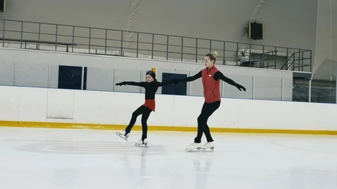 Professional figure skating trainer teaching small girl on ice arena Video stock 102337487