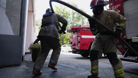 Professional firemen in uniform running with a fire hose to place of emergency Stock Footage 306321423