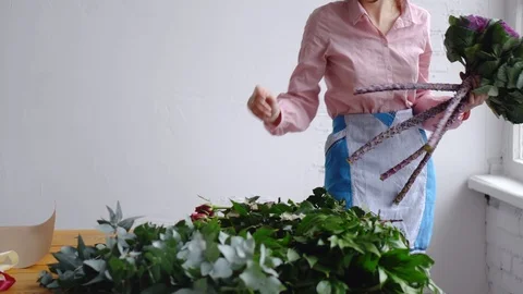 A professional florist adds one-on-one unusual purple flowers to the workplace. Stock Footage 86219619
