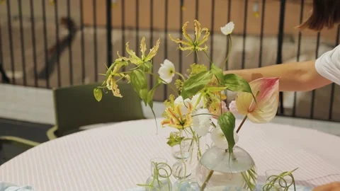 Professional florist decorates table in restaurant on outdoor terrace. Without Stock Footage 318064796