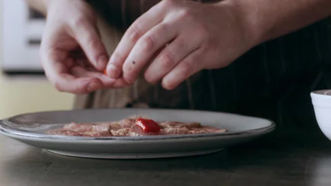Professional focused chef carefully placing sliced red peppers on top of pieces Stock Footage 199456082