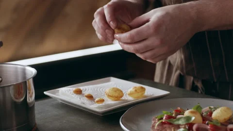 Professional focused chef carefully placing small baked potato pieces onto a pla Stock Footage 199458489