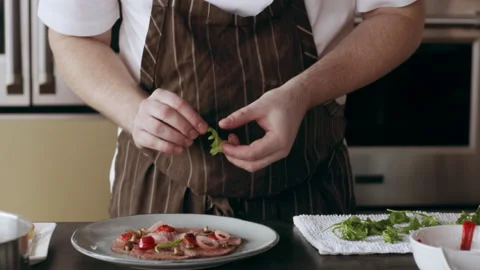 Professional focused chef carefully placing ingredients onto a plate in interior Stock Footage 199462412