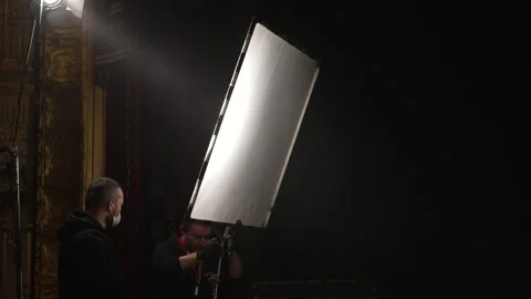 Professional gaffers adjust light diffuser when shooting scene from movie Stock Footage 165300070