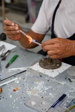 Professional glassblower using a torch and glass tube to create glass jewelry Stock Photos