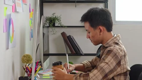 Professional graphic designer working on computer while drinking coffee in Stock Footage 336729193