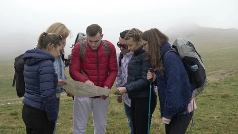 Professional guide man explaining the route to young tourists with backpacks  Video stock 86220838