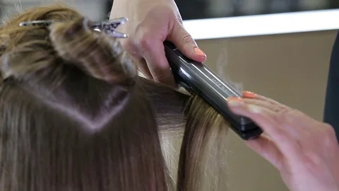 Professional hairdresser stylist curling up teen girl hair Stock Footage