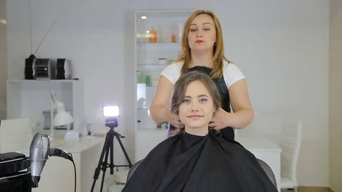 Professional hairdresser, stylist finishes hairstyle for teen girl Stock Footage