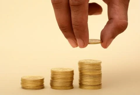 Professional Hand Putting on Stack of Golden Coins Stock Photos