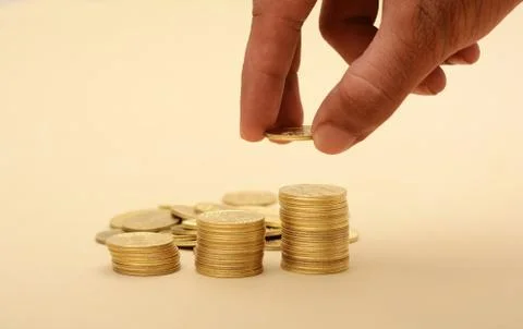 Professional Hand Putting on Stack of Golden Coins Foto stock