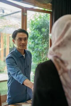 Professional handshake between a man and a woman in a bright, modern office.. 스톡 사진