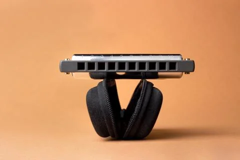 A professional harmonica lies on an open black case, with holes in the frame. Stock Photos