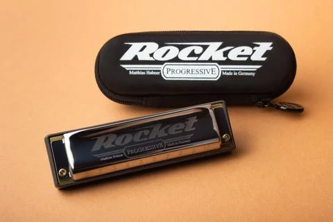 A professional Hohner Rocket diatonic harmonica next to its closed black case Stock Photos