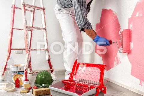 Professional house painter at work painting the wall Stock Photos