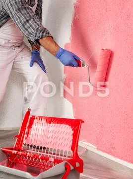Professional house painter at work painting the wall Stock Photos