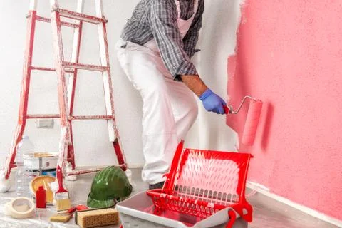 Professional house painter at work painting the wall Stock Photos