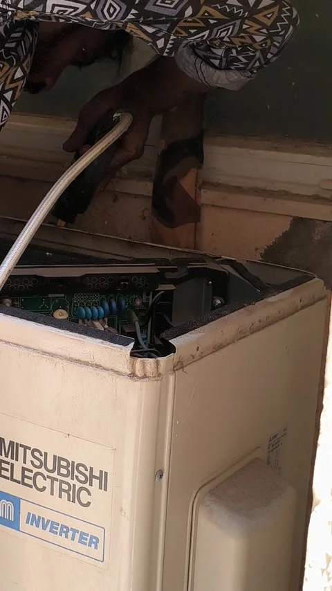 A professional HVAC worker performing routine maintenance on a split AC Stock Footage 334677566