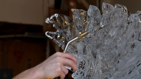 Professional ice carver using blowtorch on ice sculpture. Fire and ice Stock Footage 128387180