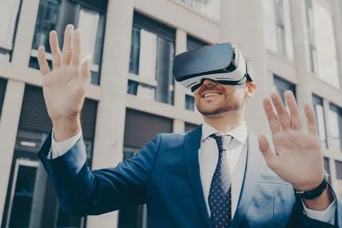 Professional impressed worker standing outside alone and using VR glasses to Stock Photos