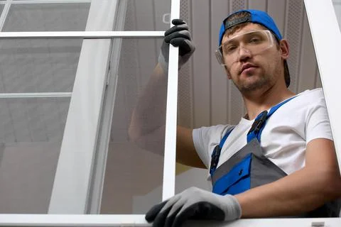 Professional installer in work uniform, standing window in protective glasses Stock Photos